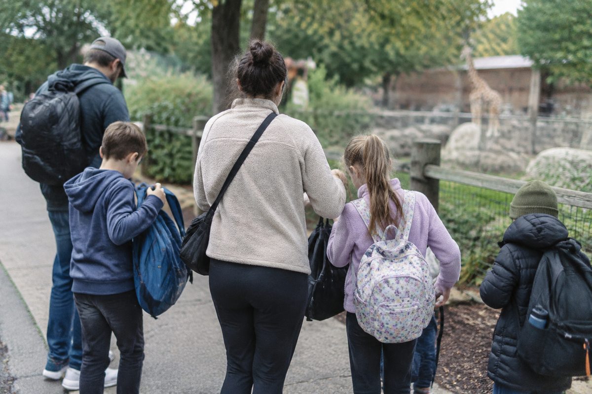 A group gathering their bags beside a zoo walkway