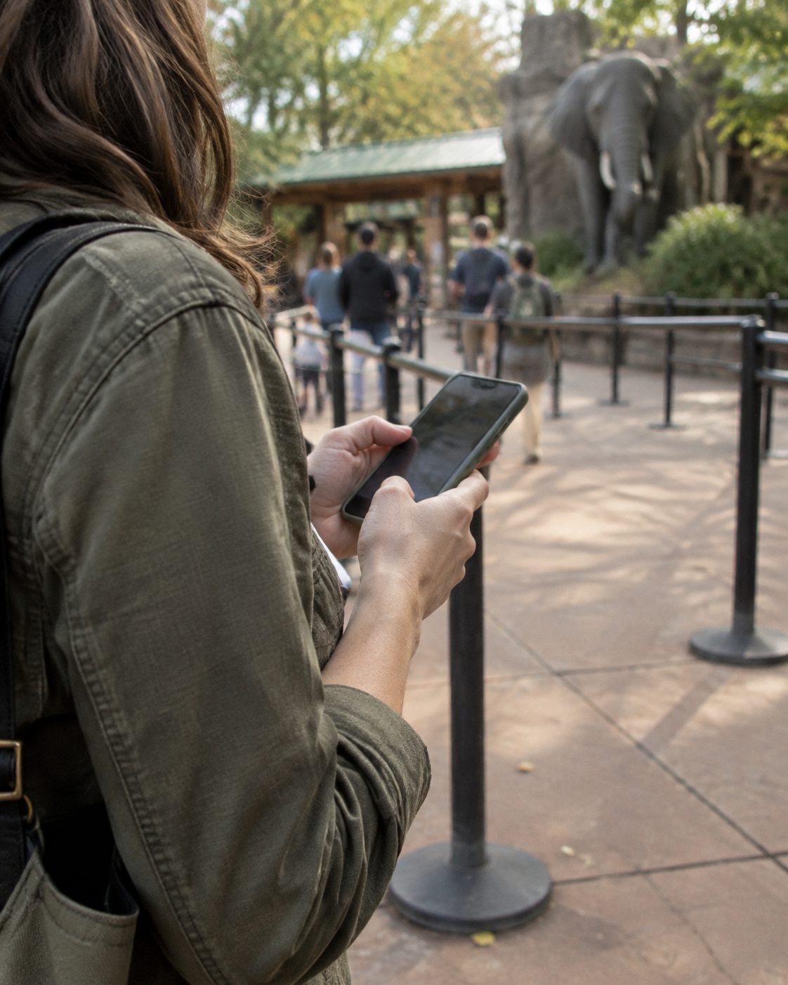 Visitor checking a phone beside an outdoor queue rail